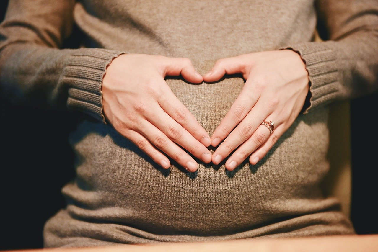 אישה בהריון מניחה את ידיה על הבטן ההריונית שלה